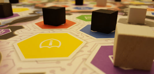 Board game with colorful tiles and black cubes on a patterned surface