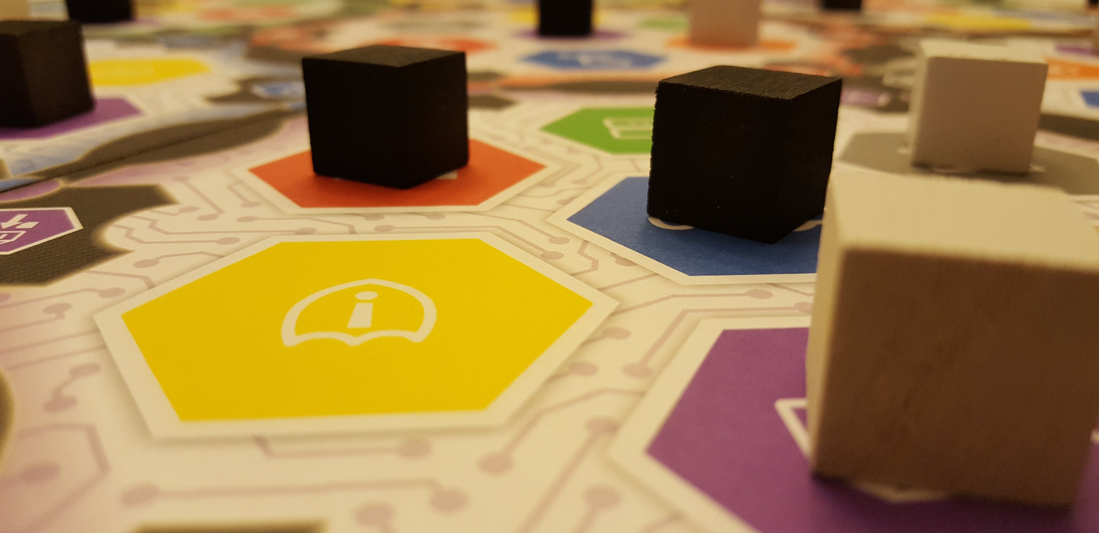 Board game with colorful tiles and black cubes on a patterned surface